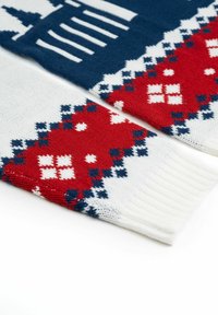 Sciarpa lavorata a maglia con un motivo blu, bianco e rosso. Accenti rossi presentano disegni geometrici con quadrati bianchi. Estremità bianche a coste.