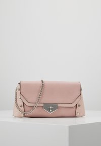 Růžová kabelka z umělé kůže s klopou, stříbrným řetízkem a metalickým svorem. Na okrajích jsou dekorativní hroty.