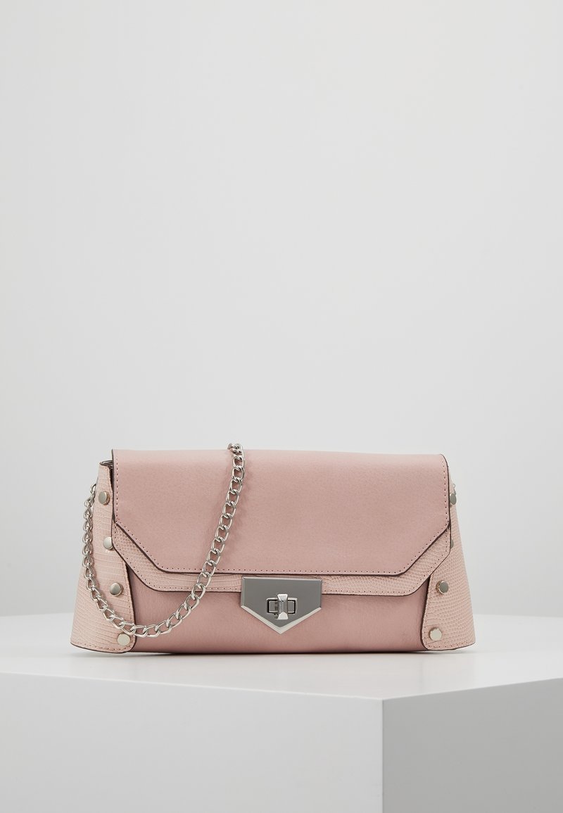 Růžová kabelka z umělé kůže s klopou, stříbrným řetízkem a metalickým svorem. Na okrajích jsou dekorativní hroty.