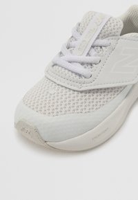 Svijetlosivi atletski tenisice s prozračnim mrežastim gornjim dijelom, glatkim teksturiranim detaljima i ravnim vezicama. Na potplatu se nalazi oznaka "Fresh Foam".