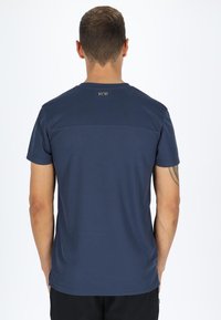 Marineblå T-shirt med korte ærmer lavet af glat stof. Har en subtil tekstur og et lille logo-tag bagpå nær halsudskæringen.