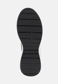 Suela de zapato de goma negra con agarre texturizado, que presenta surcos verticales y el nombre de la marca "GUESS" en relieve, ubicado en el centro.