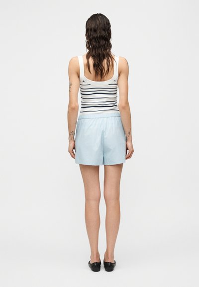 Ανοιχτό μπλε σορτς με ελαστική μέση, συνδυασμένα με εφαρμοστό λευκό αμάνικο τοπ με ναυτικούς οριζόντιους ρίγες. Ομαλή υφή.