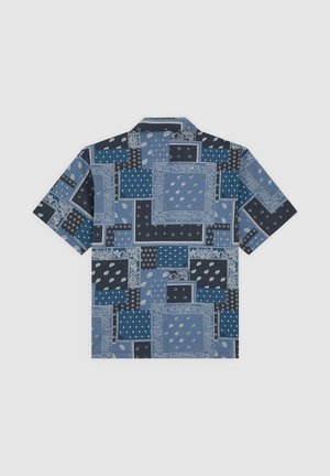 Lyhythihainen paita sinisen sävyissä, jossa on tilkkutäkkikuosi useilla eri kuoseilla, mukaan lukien paisley-kuvio ja geometriset muodot.