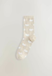 Beige sukat, joissa on toistuva kuvio valkoisista kurpitsoista, joissa on vaaleanruskeat varret. Valmistettu pehmeästä, teksturoidusta materiaalista.