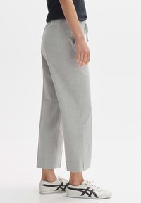 Gray, tailored, cropped pants with a drawstring waist, side pockets, and subtle texture, paired with white sneakers.