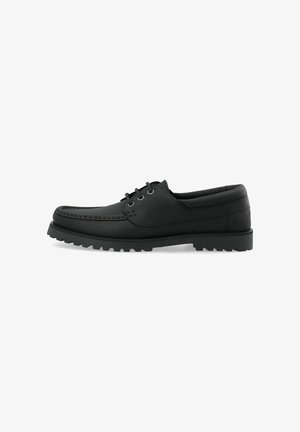 Chaussure noire en cuir à lacets avec semelle épaisse crantée et col rembourré, vue de côté sur fond blanc.
