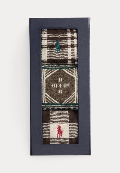 Tre par mønstrede sokker i en marineblå eske. Inneholder nyanser av brunt, grønt og krem i ulike design, med en brodert logo.