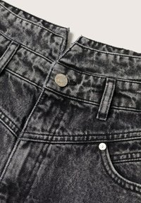 Taille de jean en denim noir acid-wash avec passants pour ceinture, fermeture par bouton, et poche avant visible sur un fond clair.