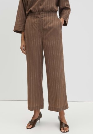 Pantaloni marroni a gamba larga con righe sottili abbinati a un top coordinato, indossati con sandali marroni con tacco e punta aperta, mostrati da metà busto ai piedi.