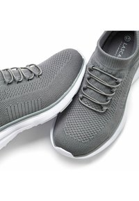 Gray knit sneakers with a textured surface, elastic lace design, and a white rubber sole, featuring a low-top silhouette.