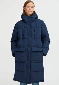 Navy blue padded long coat with a high collar, two front pockets, and a zip closure. Features a smooth texture and adjustable hood.
