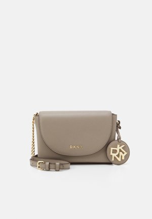 Křížová taška DKNY z taupe kůže se zlatým řetízkem, klopovým zapínáním a kulatým přívěskem s logem visícím po straně.