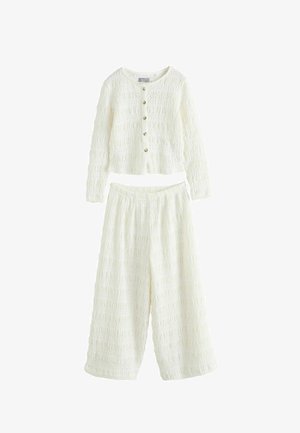 Balts divdaļīgs komplekts ar teksturētu audumu, kas sastāv no garroku pogas crop topa un platām biksēm, izgatavots no viegla auduma.