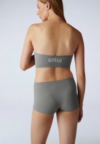 Szary ribbed bandeau z logo na plecach, w połączeniu z dopasowanymi spodniami o niskim stanie. Materiał jest gładki z lekko elastycznym wykończeniem.