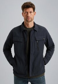 Marineblaue Jacke aus leichtem Stoff, mit zwei Brusttaschen, einer Reißverschlusstasche und einer knöpfbaren Vorderseite mit einem Kragen.