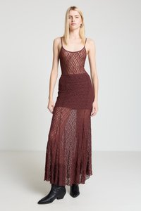 Burgundy lace maxi dress with a fitted bodice and flared hem. Features thin straps and intricate, open patterns. Paired with black ankle boots.