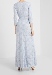 Maxiklänning i ljusblå spets, med en figursydd bodice, trekvartslånga ärmar och en utsvängd kjol med blommönster och dragkedja i ryggen.