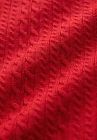 Rood gebreide stof met een kabelpatroonstructuur, met verhoogde steken en een zachte, licht pluizige uitstraling.