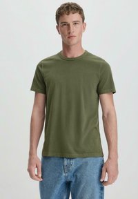 Olivgrünes Baumwoll-T-Shirt mit Rundhalsausschnitt und kurzen Ärmeln, das eine glatte Textur und ein minimalistisches Design aufweist. Keine sichtbaren Logos.