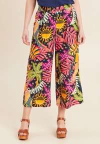 Wijde broek in donkere stof met gedurfde, kleurrijke bloemen- en zonmotieven. Bevat een comfortabele tailleband en zakken.
