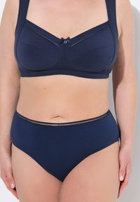 Set di reggiseno e mutandine a vita alta di colore blu navy, con accenti in pizzo e un piccolo fiocco sul reggiseno. Tessuto morbido e elastico.