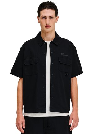 Czarna koszula z krótkim rękawem z zapięciem na guziki, dwiema kieszeniami na piersi i subtelnym detalem z logo. Wykonana z gładkiego materiału.