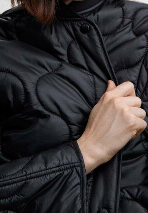 Black quilted jacket featuring a smooth, shiny texture, snap button closure, and distinct padded design with subtle curves.
