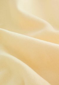 Zachte, lichte, lichtgele stof met een gladde textuur, voorzien van fijne breipatronen en een zachte val. Ideaal voor kleding of bekleding.