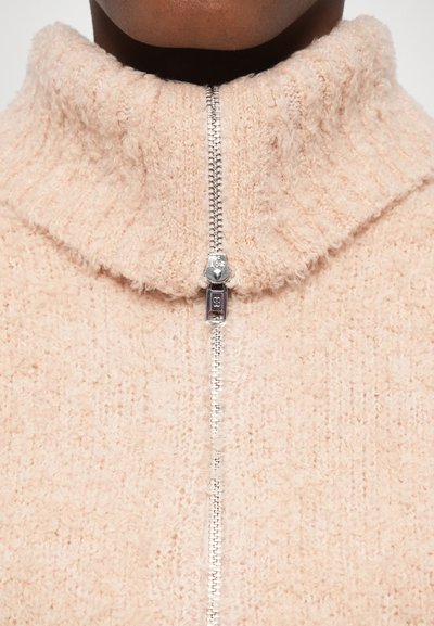 Felpa zip-up rosa chiaro con colletto alto, texture morbida e dettagli metallici argento, caratterizzata da un motivo a coste.