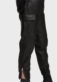 Svarta läderjoggers med slim fit, med sidofickor, elastiska manschetter och dragkedja i fållen för justerbar passform.