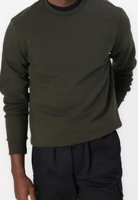 Mörkgrön sweatshirt i mjukt tyg, med rund halsringning och långa ärmar, samt ribbade muddar och nederkant.