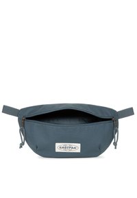 Pochette Eastpak in tessuto blu scuro, forma ovale, chiusura con zip, manici superiori e etichetta del marchio sul fronte. Materiale liscio e resistente.