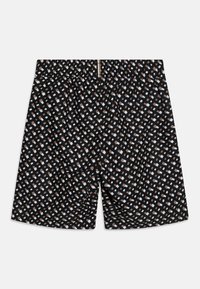 Shorts noirs avec un motif géométrique en blanc et marron clair. Présentent une taille élastique et une coupe large. Texture de tissu douce.