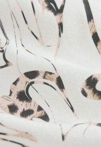 Witte stof met een abstracte luipaardprint in zwart en beige, met een gladde textuur en vloeiende lijnen.
