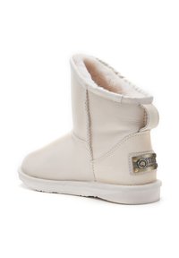 Biele kožené členkové čižmy s jemným, svetlým kožušinovým podšívkou. Obsahujú plochú gumovú podrážku a dekoračnú označenú visačku s kovovými akcentmi.