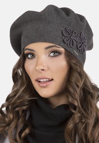 Graue Mütze aus Strickmaterial mit einem lockeren Design, verziert mit zwei dunklen Blumenapplikationen, von denen jede mit einer kleinen Perle geschmückt ist.