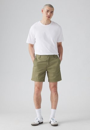 Khaki shorts i en bomuldsblanding med klassisk snit og sidelommer. Kombinationen af en ensfarvet hvid bomulds t-shirt og hvide sportsstrømper.