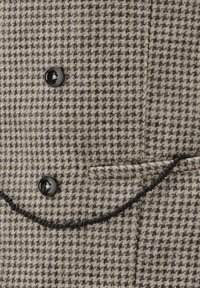 Hahnentrittmuster-Stoff in Beige und Braun. Verfügt über zwei schwarze Knöpfe, eine paspelierte Taschenverzierung und eine strukturierte Oberfläche.