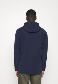 Mörkblå vattentät jacka med huva, med en enkel design och något längre bakstycke. Tillverkad av slät, lätt tyg.