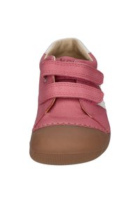 Pink fabric shoe with two Velcro straps, rounded toe, light tan rubber sole, and white accents on the side. Smooth texture and casual design.