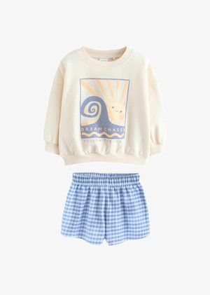 Mikina v off-white bavlněném materiálu s grafikou znázorňující slunce a vlny; spárována s modrými kostkovanými šortkami s elastickým pasem.