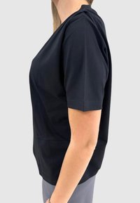 Sort t-shirt med korte ærmer, løs pasform, rund halsudskæring og glat bomuldsmateriale. Sidevinklen fremhæver detaljen på skuldersømmen.