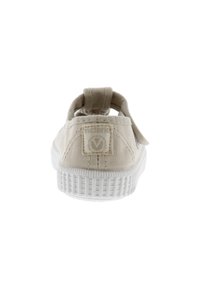 Sneaker in tela beige con retro arrotondato, dotata di un tappo per il tallone a morbido anello, suola in gomma bianca texturizzata e un logo discreto cucito sul tallone.