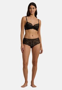 Svart spetsbehå med underwire och justerbara band, kombinerad med matchande spetsshorts i pojkstil med blommönster och scallopade kanter.