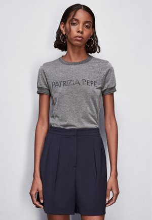 T-shirt grigia aderente con maniche corte e bordi più scuri, che presenta il testo "PATRIZIA PEPE" in un font bold. Abbinato a pantaloni corti a pieghe blu navy.