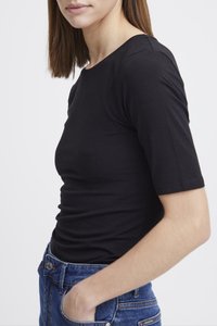 Schwarzes T-Shirt mit kurzen Ärmeln, leichtes Baumwollmaterial, figurbetontes Design, klassischer Rundhalsausschnitt, präsentiert mit blauen Jeans aus Denim.