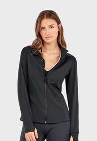 Crna sportska jakna na zatvaranje, prilagođenog kroja, dugih rukava s otvorima za prste, glatkog materijala, suptilnim detaljima šavova i visokim ovratnikom.