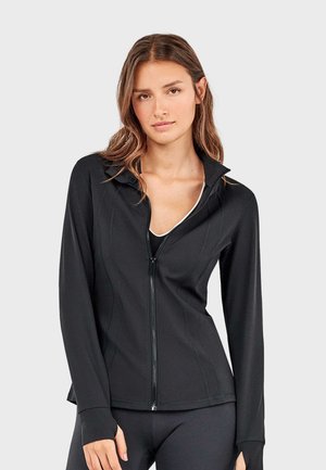 Schwarze, enganliegende Sportjacke mit Reißverschluss, langärmlig mit Daumenlöchern, glattes Material, dezente Nahtdetails und hohem Kragen.