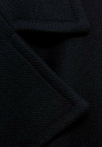 Črno teksturirano blago s herringbone vzorcem, ki ima oster, angularen pregib in gladko površinsko obdelavo.